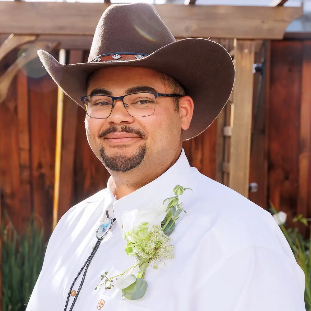 Photo of a smiling man with a tidy goatee in a dress shirt and cowboy hat