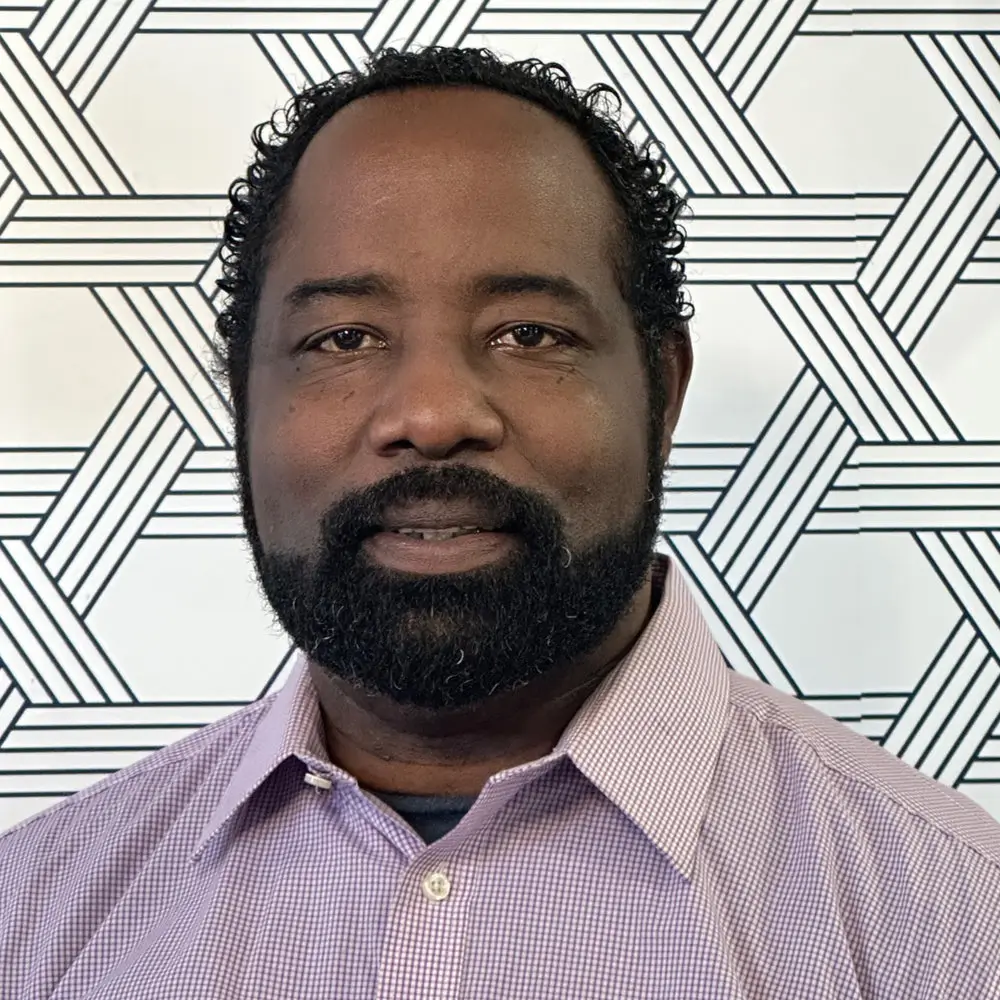 Photo of a smiling man with a trimmed beard in a dress shirt
